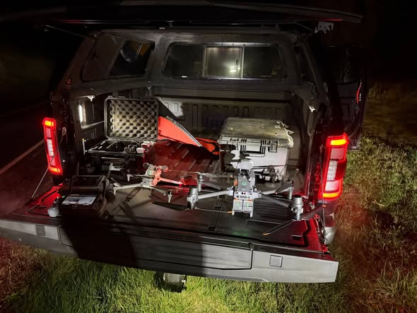 Drone and equipment cases staged in a truck bed at night before a search